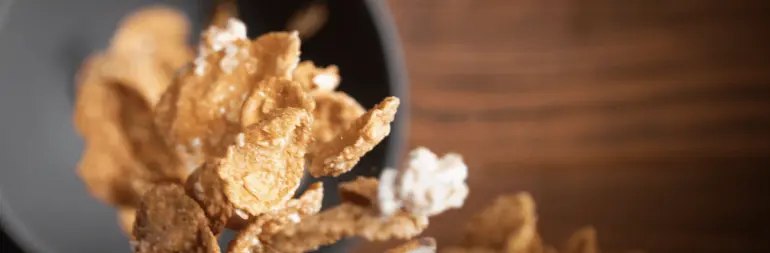 Une cascade de céréales Oatmeal Crisp tombant d'une boite dans un bol en dessous.